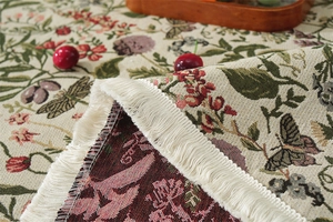 Detail of vintage floral jacquard tablecloth with delicate white fringe and butterfly motifs
