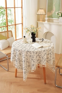 Close-up of cream floral cotton tablecloth with elegant white fringe tassel edges