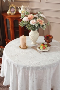 Close-up of white cotton tablecloth with hollow embroidery and ruffled lace edges