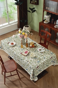 Close-up of vintage floral tablecloth with colorful birds and white fringe tassels