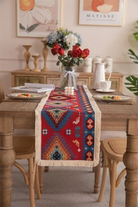 Macro detail of red bohemian table runner featuring ethnic jacquard patterns and tassels