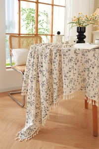 Detail of floral cotton tablecloth featuring cream jacquard pattern and elegant fringe edges