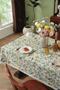 Macro view of floral jacquard tablecloth with bird patterns and beige tassel fringe edge