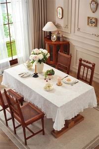 Close-up of white cotton tablecloth featuring ruffle edges and delicate floral embroidery