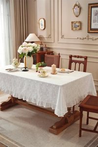 Detail of white cotton tablecloth with geometric jacquard and ruffled edges in vintage style