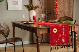 Detailed close-up of festive red table runner with gold New Year embroidery and tassels