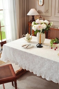 Close-up of ivory cotton tablecloth featuring intricate floral jacquard and elegant ruffles