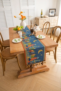 Detail of blue jacquard table runner with moon, castle patterns and elegant tassels