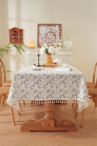 Detailed texture of cotton jacquard tablecloth with black floral print and fringe tassels