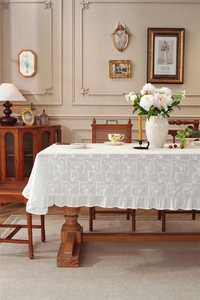 Close-up of white cotton tablecloth with floral embroidery and elegant ruffle edge