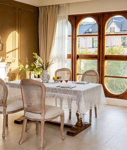 Detailed view of white French lace tablecloth with leaf patterns and elegant tassels