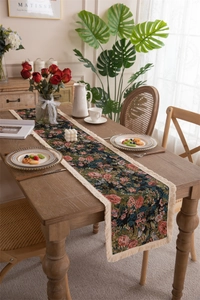 Close-up of vintage floral table runner with elegant cream tassels on a wooden table