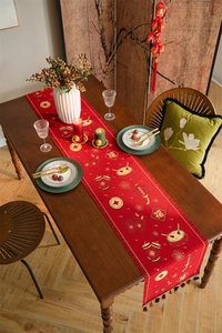 Macro view of red festive table runner with golden New Year patterns and brown tassels