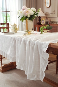 Close-up of white cotton tablecloth featuring floral embroidery and ruffled edge details