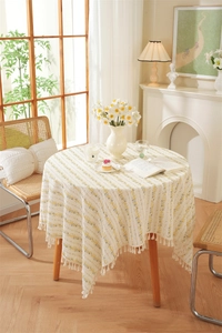 Detailed texture of cotton floral tablecloth featuring cream fabric and white cotton tassels