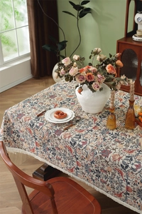 Close-up of vintage floral jacquard tablecloth with elegant birds and tassel fringes