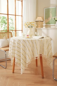 Detail of floral cotton tablecloth with white tassels in a French country style setting
