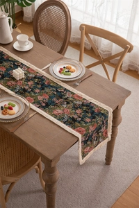 Detail of vintage floral jacquard table runner with delicate cream fringe tassels