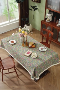 Close-up of floral jacquard tablecloth with white tassel fringe in a vintage room