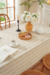 Detail of floral cotton tablecloth with white fringes and vibrant yellow floral patterns