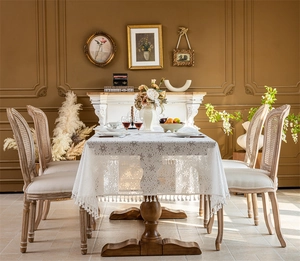 Detail of white lace tablecloth featuring snowflake patterns and elegant fringe edges