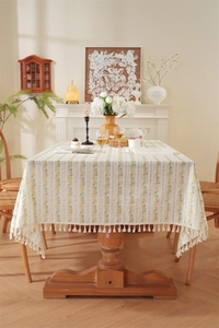 Detailed close-up of floral strip patterns and white fringe tassels on cotton tablecloth