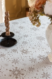 Close-up of winter snowflake patterns on a textured beige cotton linen tablecloth