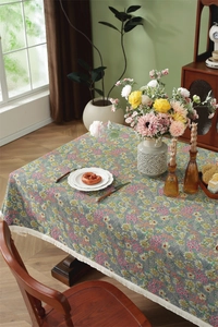 Detail of vintage floral tablecloth featuring intricate fringes on a wooden table