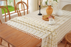 Close-up of floral cotton tablecloth featuring white tassels and yellow flower pattern