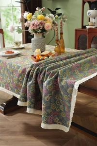 Close-up of vintage floral tablecloth with intricate fringe edges and colorful botanical patterns