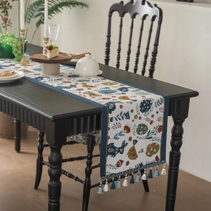 Easter table runner with blue rabbits, floral eggs and tassels on a long wooden table