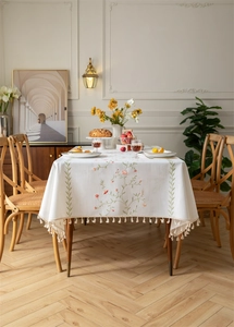 Detail of embroidered floral patterns and beige tassels on cotton linen tablecloth