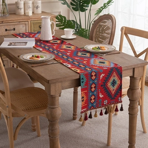 Ethnic red table runner with geometric patterns and fringe tassels on wood table