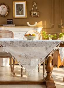 Detailed view of white floral lace tablecloth featuring delicate fringes and snowflake patterns