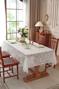 Dettaglio della tovaglia in pizzo bianco con motivi floreali jacquard e bordi ondulati