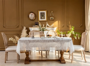 Close-up of white lace tablecloth with tropical leaf patterns and fringed tassels detail