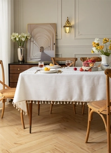 Detailed embroidery of floral patterns and woven fringe on a beige tablecloth
