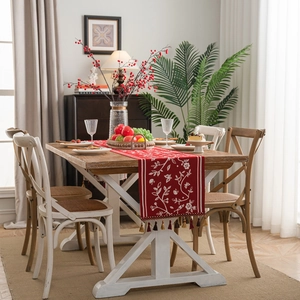 Red festive table runner with white floral embroidery and colorful tassels for dining decor