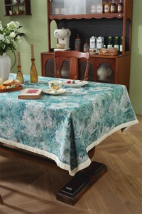 Detailed view of vintage jacquard tablecloth with teal floral patterns and fringe trim