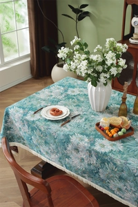 Detail of vintage floral jacquard tablecloth with elegant white fringe trim on wood table