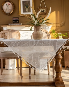 Close-up of white lace tablecloth featuring hollow flower texture and tassel fringe detailing
