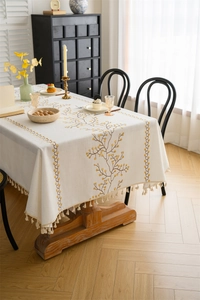 Detail of floral embroidery and beige tassels on a cotton linen rectangular tablecloth