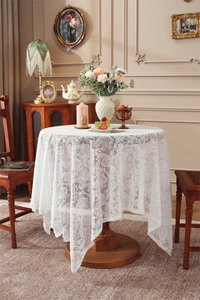 Dettaglio della tovaglia in pizzo bianco con motivi floreali vintage e drappeggio elegante