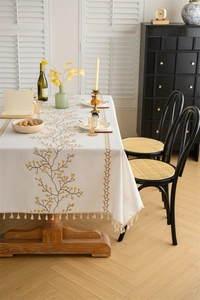 Detail of floral embroidery on a cream rectangle tablecloth with yellow berry patterns
