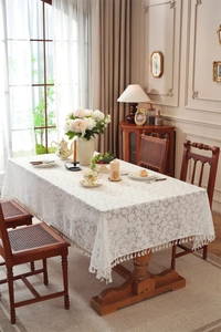 Close-up of white lace tablecloth featuring leaf patterns and elegant tassel fringe edges
