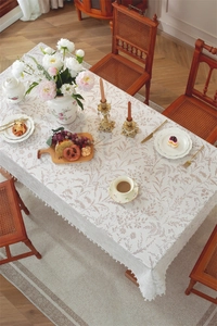 Detail of French lace tablecloth with brown leaf patterns and white pompom fringe trim