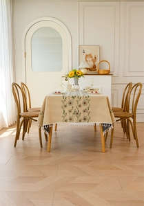 Detail of floral jacquard tablecloth with daisy embroidery and white tassel fringe