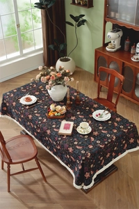 Detail of vintage floral tablecloth featuring red flowers and birds with fringe edges