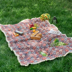 Close-up of jacquard floral pattern tablecloth with white tassels on green grass