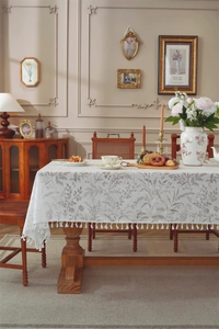 Close-up of elegant white floral lace tablecloth featuring delicate fringes and leaf patterns